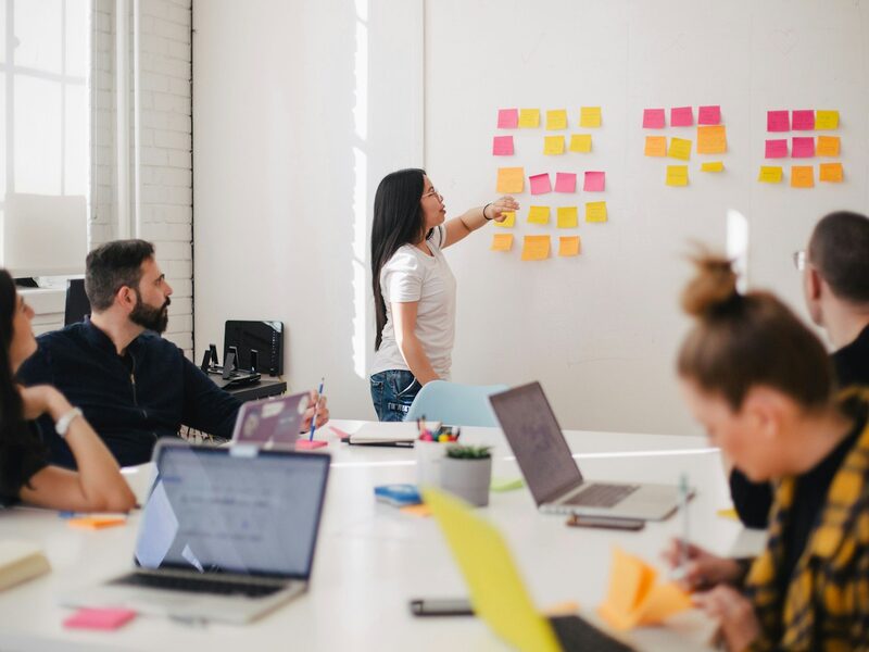 A diverse marketing team collaborating on campaign strategy around a planning wall